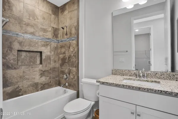 a bathroom with a granite countertop bathtub shower sink vanity and toilet