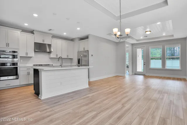 a kitchen with stainless steel appliances granite countertop a wooden floors and white cabinets