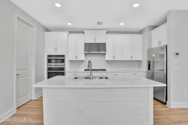 a kitchen with kitchen island a counter top space cabinets and stainless steel appliances