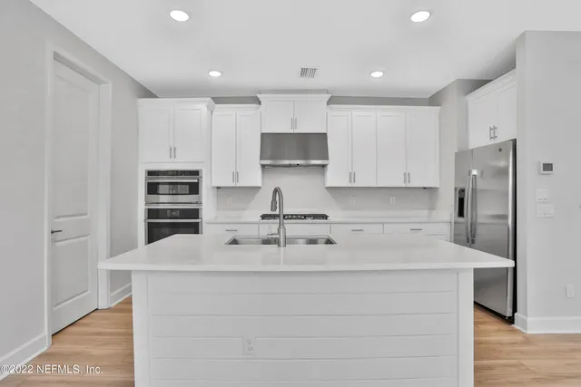 a kitchen with kitchen island a counter top space cabinets and stainless steel appliances