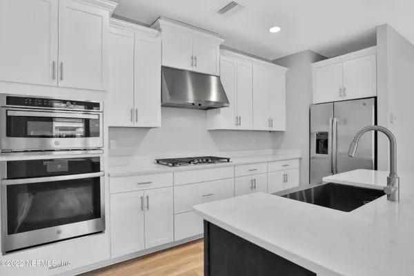 a kitchen with white cabinets and stainless steel appliances