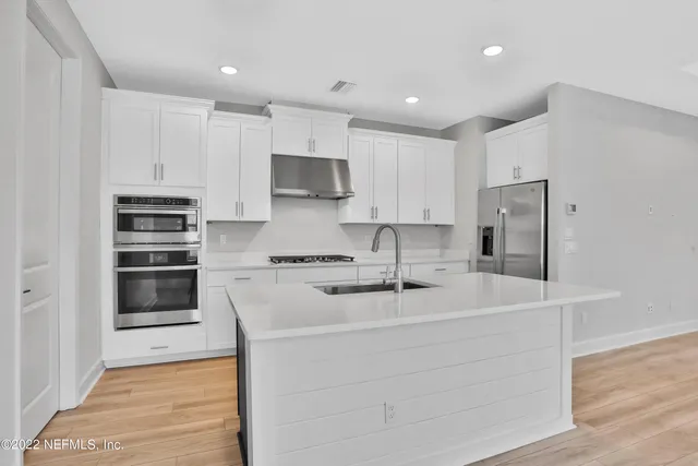 a kitchen with stainless steel appliances a stove a sink and a refrigerator