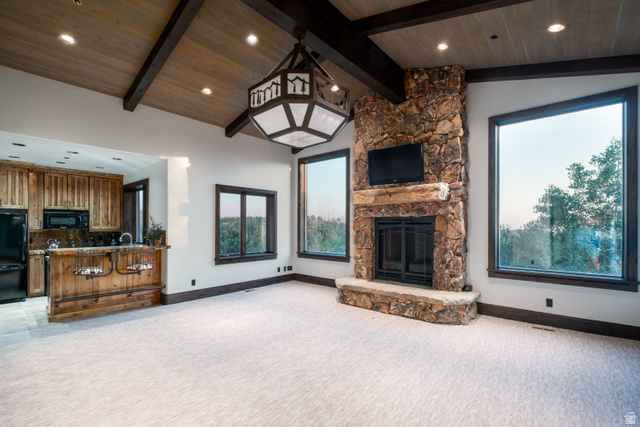 9156 Forest Road, Unit 24 Heber City, UT 84036 - Photo 35 of 42 Great room featuring a prominent stone fireplace, vaulted wood-paneled ceiling with exposed beams, and a built-in wet bar with wood cabinetry and a dark countertop