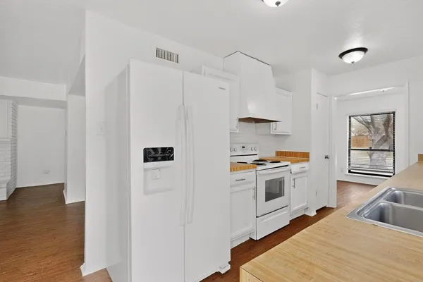 a kitchen with stainless steel appliances a refrigerator sink and white cabinets