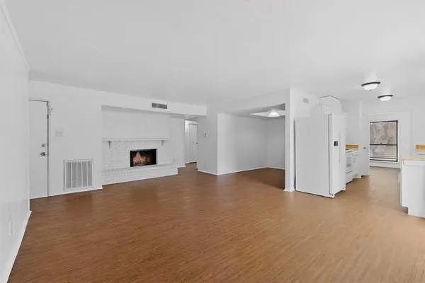 a view of empty room with wooden floor and fireplace