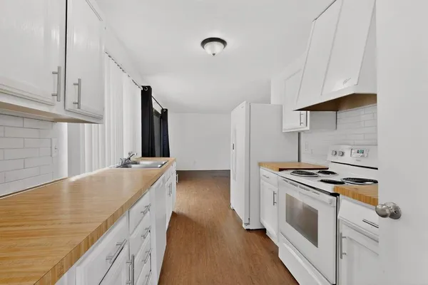 a kitchen with granite countertop a sink stove and cabinets