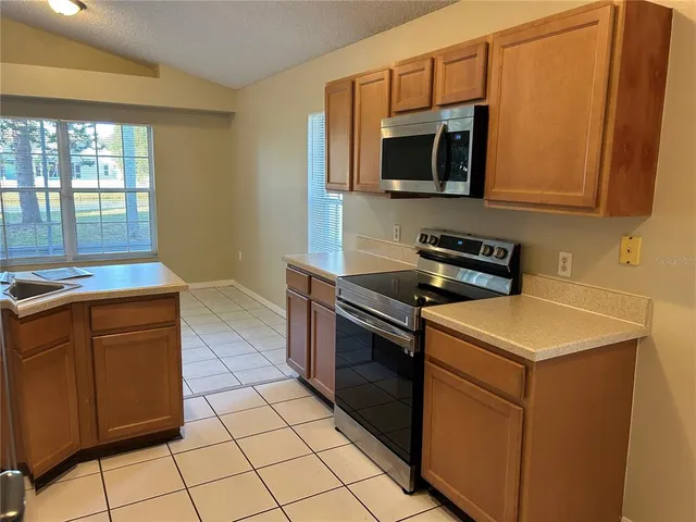 a kitchen with granite countertop a stove top oven microwave and cabinets