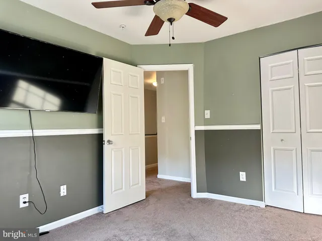 an empty room with closet and a chandelier fan