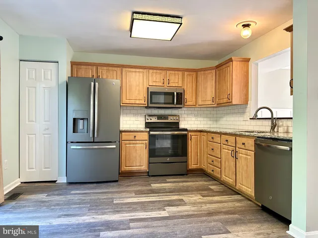 a kitchen with granite countertop a refrigerator stove and sink