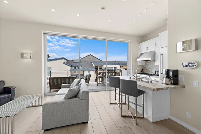 a living room with stainless steel appliances furniture a rug and a kitchen view