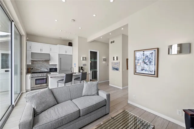 a living room with stainless steel appliances furniture and a view of kitchen