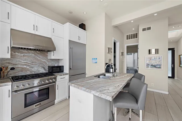 a kitchen with granite countertop kitchen island stainless steel appliances a stove refrigerator sink and cabinets