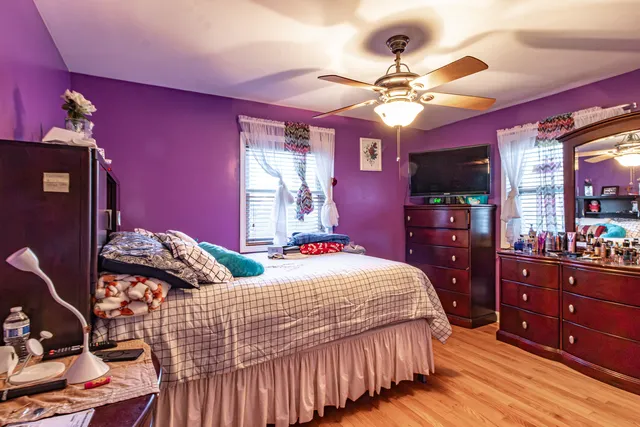 a bedroom with bed and dresser with chandelier