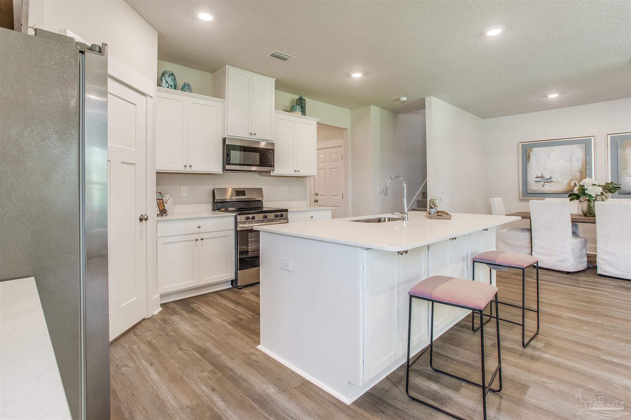 3459 Crossvine Road Cantonment, FL 32533 - Photo 6 of 38 a kitchen with stainless steel appliances kitchen island granite countertop a sink a stove a refrigerator and cabinets