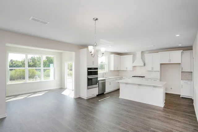 a open kitchen with white cabinets and wooden floor