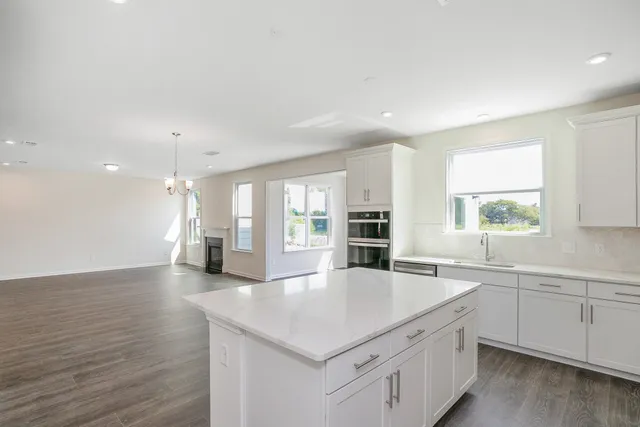 a kitchen with stainless steel appliances granite countertop a sink dishwasher a stove and white countertops with wooden floor