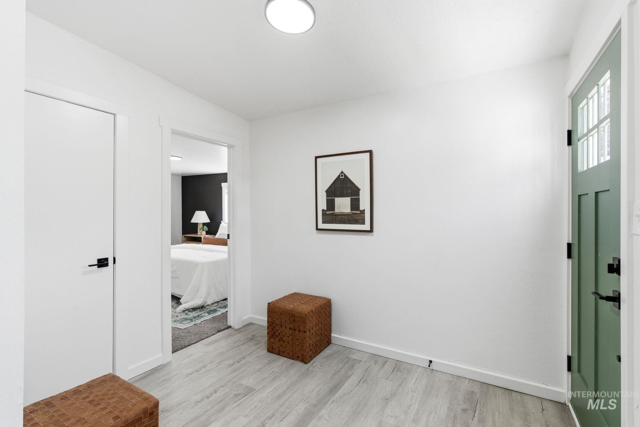 2224 Rachel Circle Boise, ID 83706 - Photo 7 of 50 Light wood-finish flooring featuring a modern recessed ceiling light, a contrasting green entry door with glass panes, and a white interior door with matte black hardware
