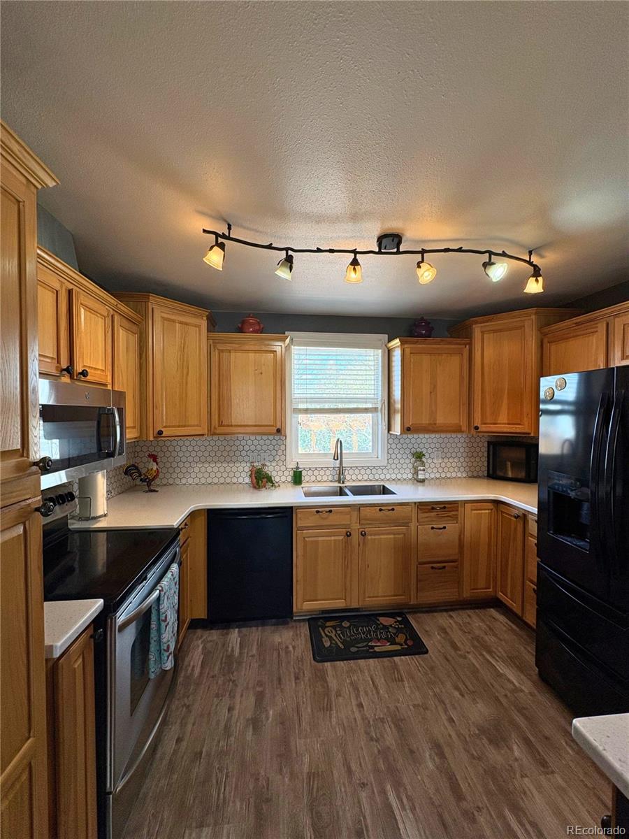323 Fairview Street Otis, CO 80743 - Photo 12 of 38 a kitchen with stainless steel appliances granite countertop a stove a sink dishwasher a refrigerator and a microwave oven on the wooden floor