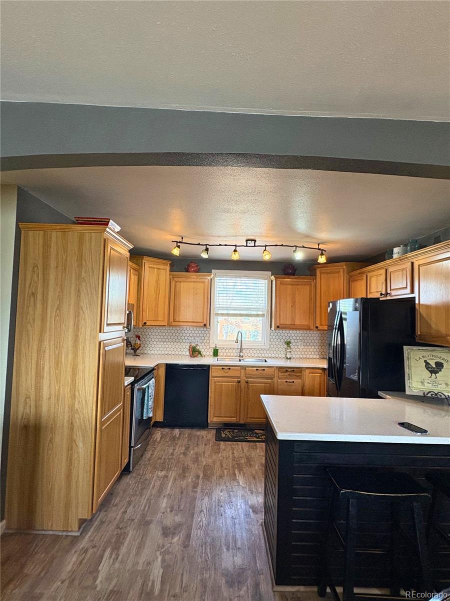 323 Fairview Street Otis, CO 80743 - Photo 13 of 38 a kitchen with stainless steel appliances wooden floor sink stove and cabinets