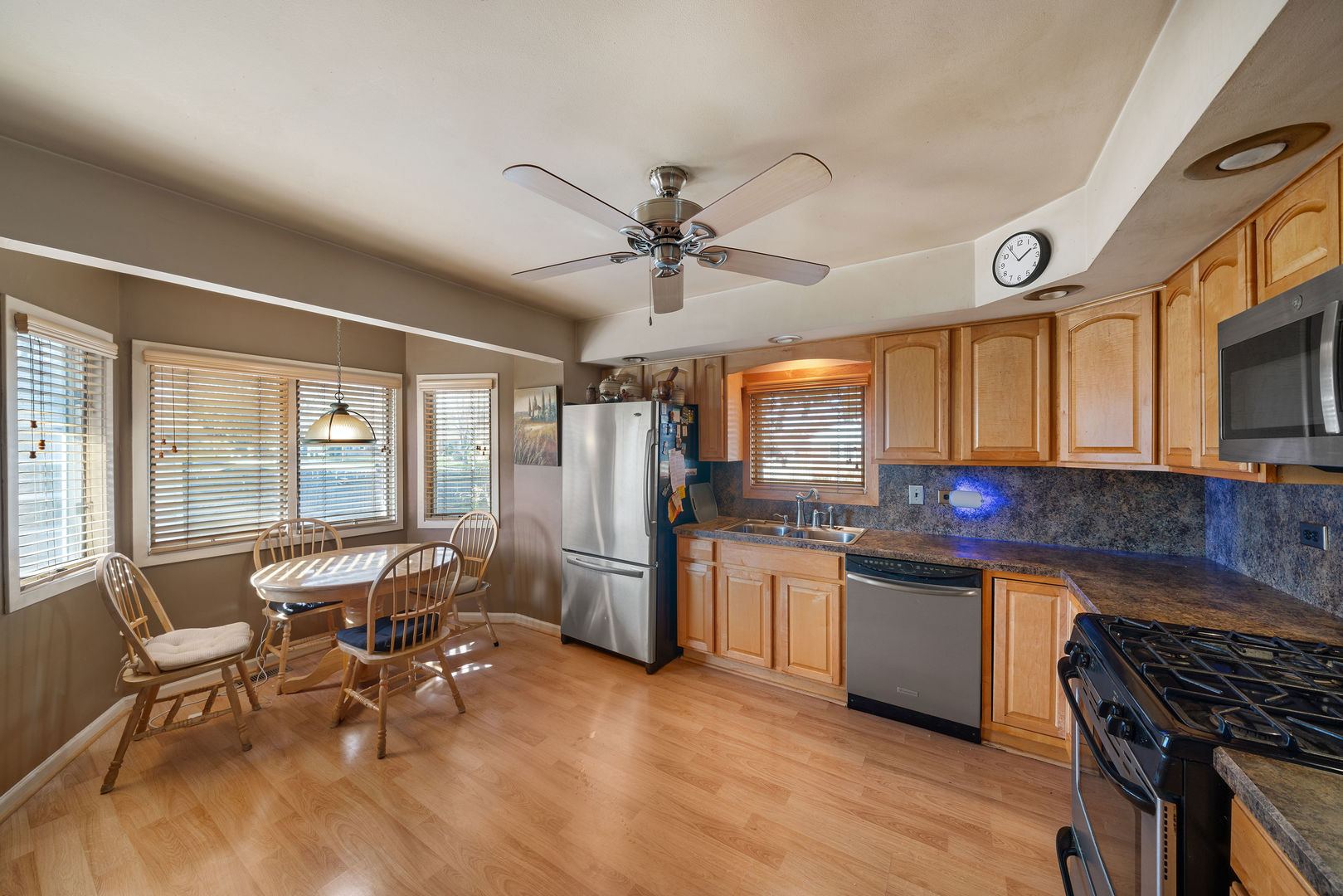 1500 Harding Avenue Berkeley, IL 60163 - Photo 11 of 22 a open kitchen with stainless steel appliances granite countertop a stove top oven a sink dishwasher a dining table and chairs with wooden floor