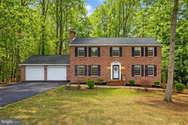 a front view of house with yard and trees in the background