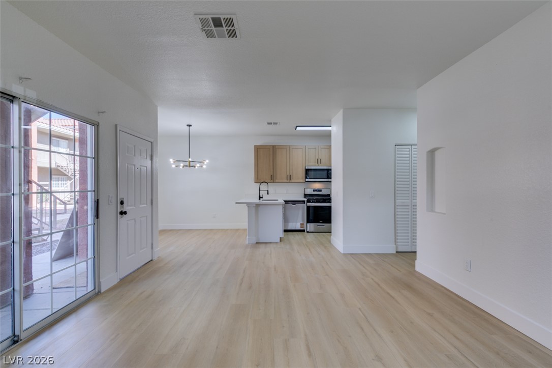 4730 East Craig Road, Unit 1085 Las Vegas, NV 89115 - Photo 22 of 23 A well-lit open-concept living space connects to a modern kitchen, featuring sleek appliances and a spacious island.