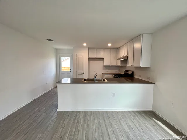 a large white kitchen with wooden floors and a sink