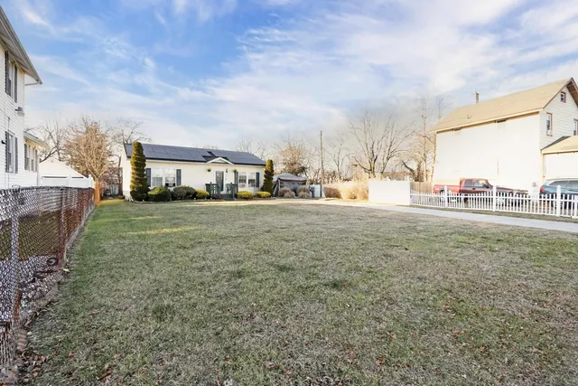 a view of yard with large trees and cars parked
