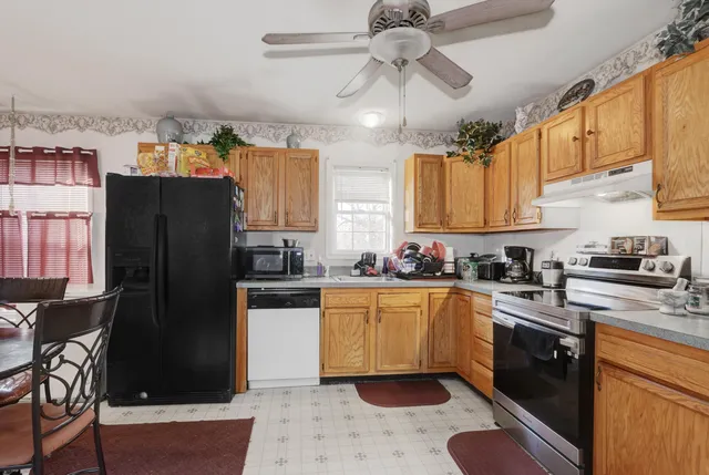 a kitchen with stainless steel appliances granite countertop a refrigerator a sink dishwasher a stove top oven a refrigerator with island and chairs