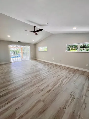 an empty room with wooden floor and ceiling fan