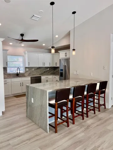 a kitchen with stainless steel appliances granite countertop a kitchen island a stove a cabinets and a chairs