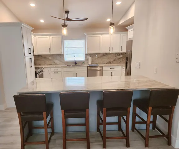 a kitchen with a dining table chairs cabinets and stainless steel appliances