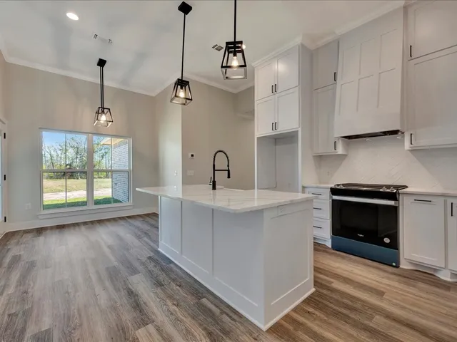 a kitchen with stainless steel appliances granite countertop a sink a stove a refrigerator and a wooden floor