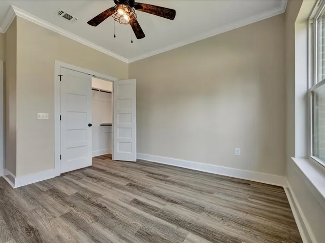 a view of empty room with wooden floor and fan