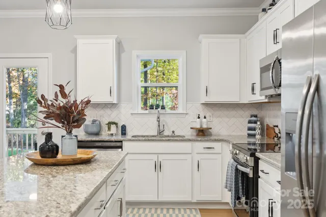 a kitchen with stainless steel appliances granite countertop a sink a stove and a refrigerator