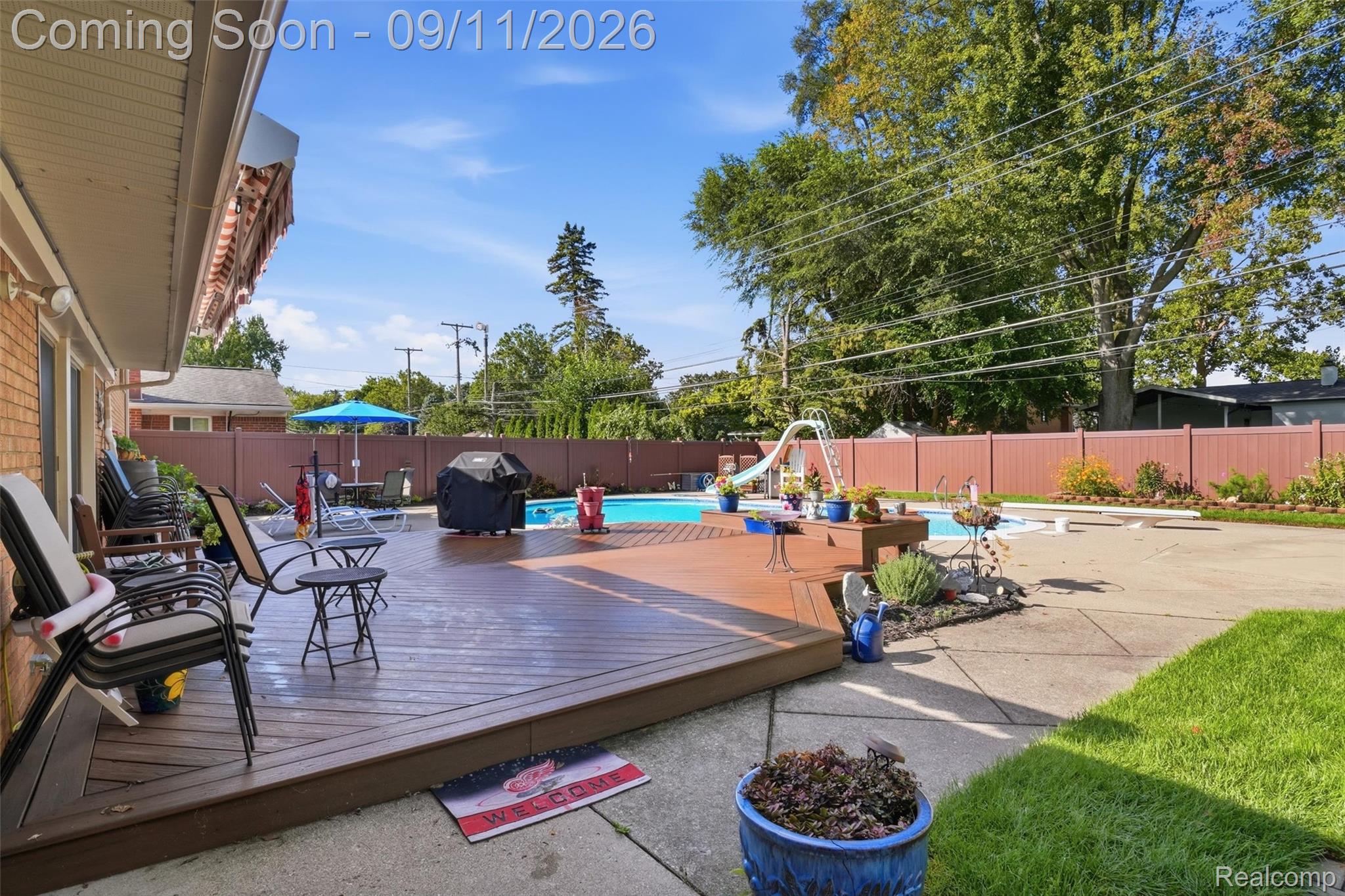 16799 Farmington Road Livonia, MI 48154 - Photo 54 of 71 Expansive backyard featuring a large swimming pool, wood-finish deck, concrete patio, and a privacy fence