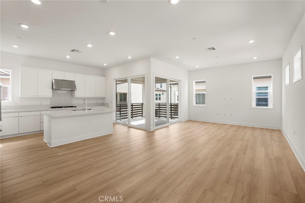 124 Tiffin Irvine, CA 92618 - Photo 6 of 26 a large white kitchen with wooden floors and white walls