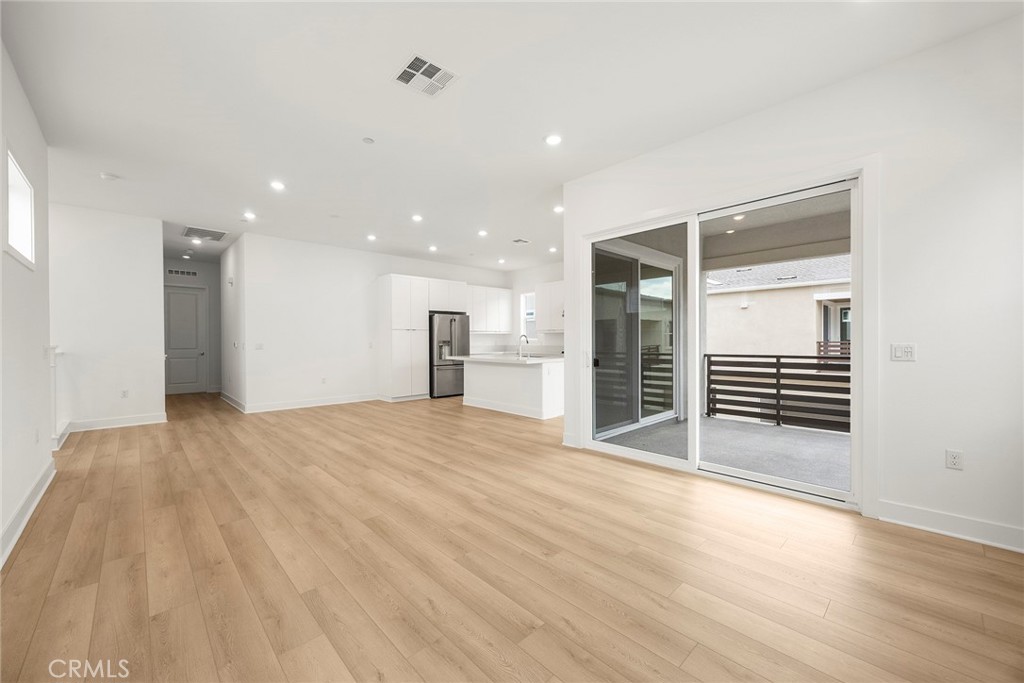 124 Tiffin Irvine, CA 92618 - Photo 7 of 26 a view of an empty room with wooden floor and a kitchen