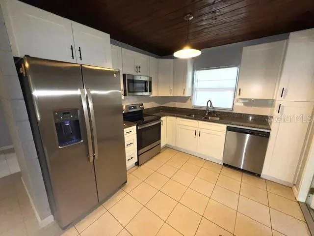 a kitchen with stainless steel appliances granite countertop a sink a stove a refrigerator and cabinets