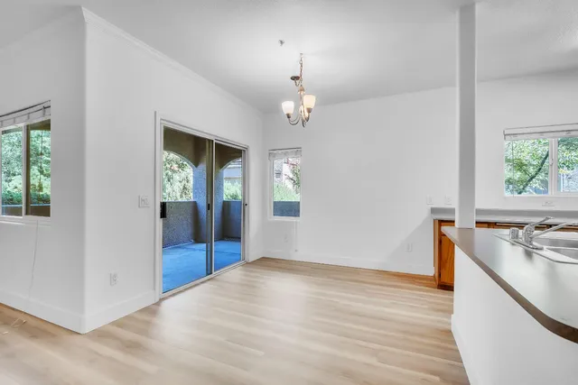 an empty room with wooden floor cabinet and windows