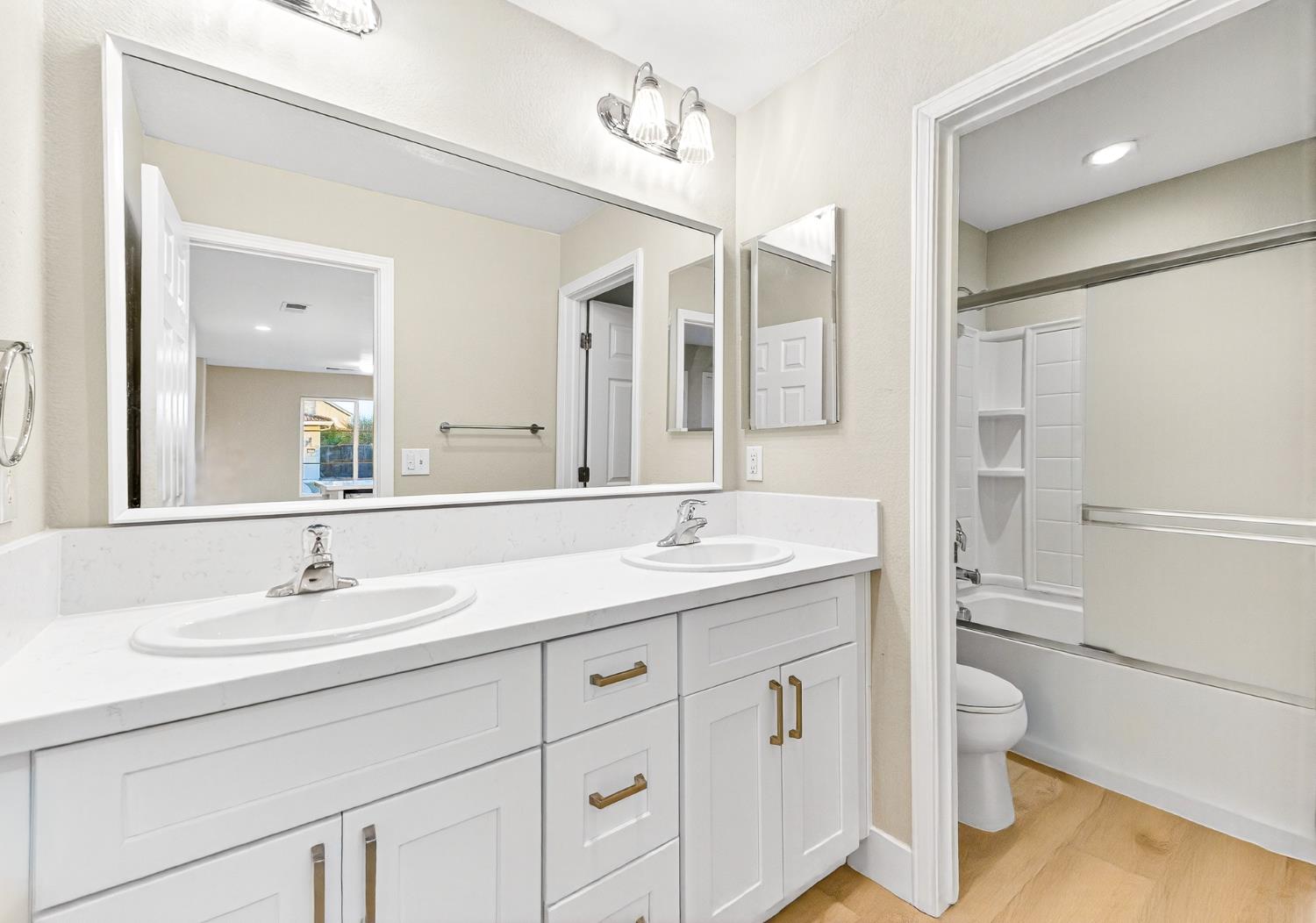 7481 Splendid Way Elk Grove, CA 95758 - Photo 23 of 41 a bathroom with a granite countertop sink a toilet and a large mirror