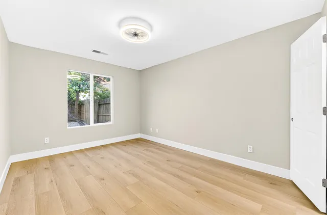 a view of an empty room with wooden floor and a window