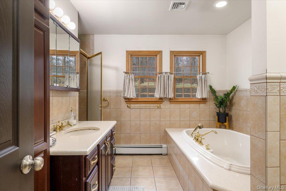 223 Bread And Cheese Hollow Road Northport, NY 11768 - Photo 19 of 32 a bathroom with a granite countertop tub a sink and a large mirror