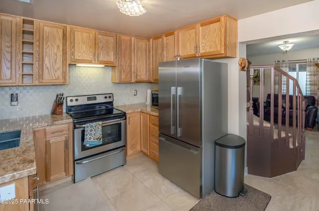 a kitchen with stainless steel appliances granite countertop a refrigerator a stove and a sink