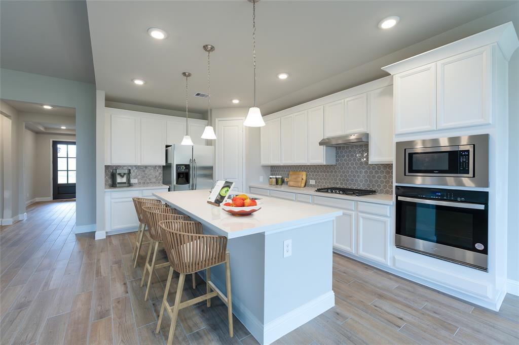 a kitchen with stainless steel appliances kitchen island granite countertop a table chairs sink and microwave