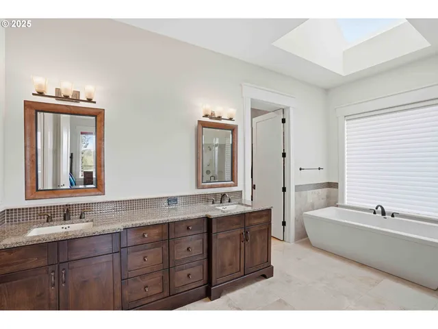 a bathroom with a sink double vanity granite tub and a mirror