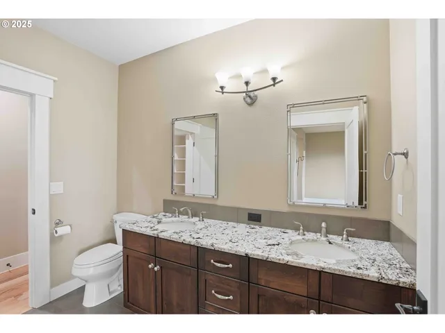 a bathroom with a granite countertop sink a toilet and a mirror