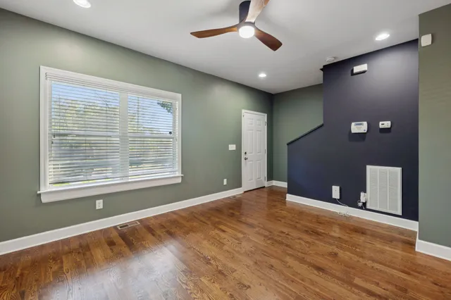 a view of an empty room with window and wooden floor