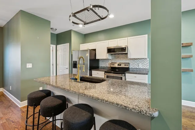 a kitchen with stainless steel appliances granite countertop a sink and a stove top oven with wooden floor