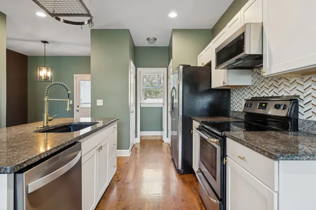 a kitchen with stainless steel appliances granite countertop a sink stove and refrigerator